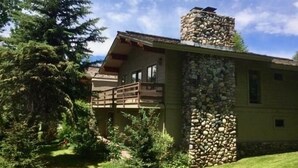 A lodge with a stone chimney, a balcony, and a view of the surrounding forest. - Ideally Located, Sun Valley Chalet (Ketchum)