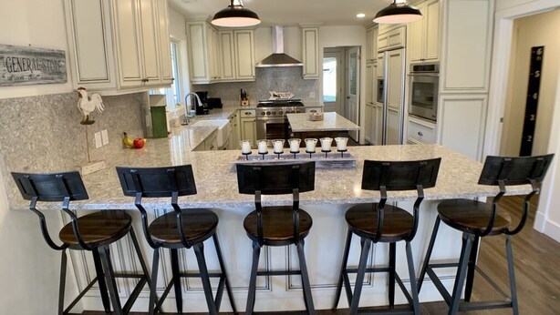A kitchen with white cabinets, a granite countertop, and a central island with bar stools. - Ideally Located, Sun Valley Chalet (Ketchum)