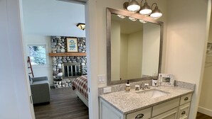 A bathroom with a granite countertop, a large mirror, and a stone wall. - Ideally Located, Sun Valley Chalet (Ketchum)