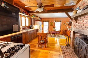 Cozy kitchen with a brick fireplace, wooden dining table, and modern appliances.
