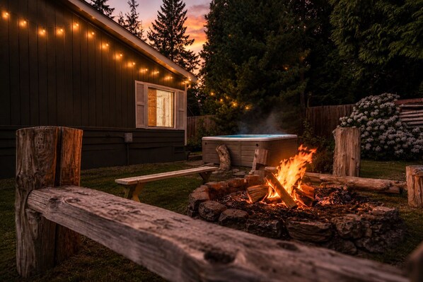 A wooden deck with a fire pit, a hot tub, and string lights.