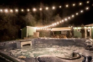 A hot tub with a hose, surrounded by a misty atmosphere, and string lights in the background. - Basecamp . Hot Tub . Sauna . Bunkhouse . Walk to Falls (Packwood)