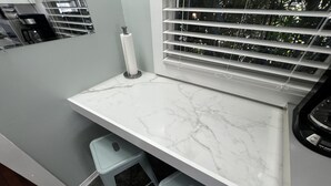 A kitchen with a marble countertop, two stools, a coffee machine, and a window with blinds. - Cute Tropical Beach Studio Walk to Ocean and All! (Long Beach)