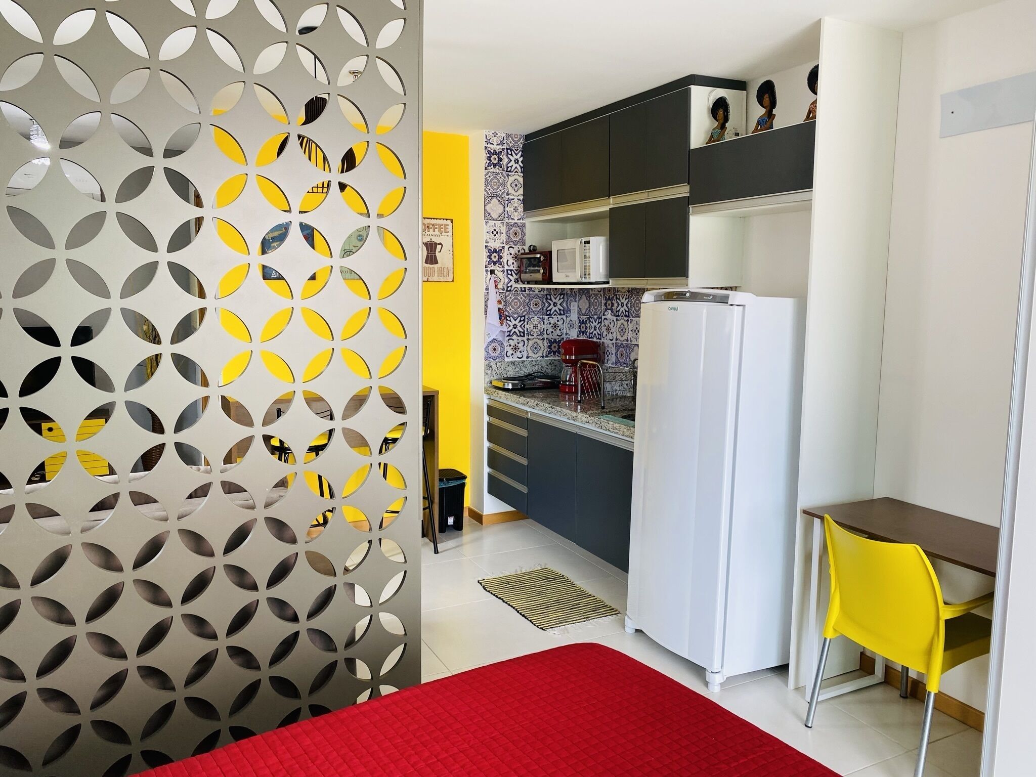 A compact kitchen with a refrigerator, microwave, and a coffee machine.