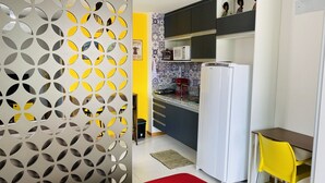 A compact kitchen with a refrigerator, microwave, and a coffee machine. - Studio (RJ)