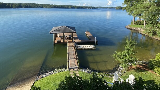 A lakeside dock with a covered seating area and a floating platform.