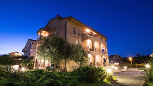 A large, multi-story building with a central courtyard, surrounded by lush greenery and illuminated by street lamps. - Vacation apartment Šanić Lopar 543a (Lopar)