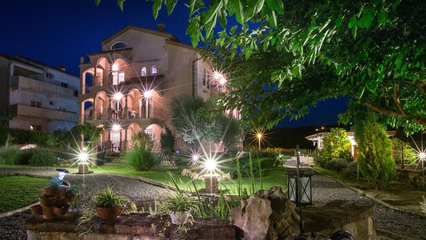 A multi-story building with a courtyard, stone walls, and potted plants. - Vacation apartment Šanić Lopar 543a (Lopar)