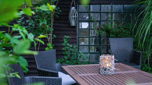 Eine Terrasse mit Korbmöbeln, einem Tisch und einer Laterne.