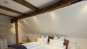 Ein Schlafzimmer mit einem hölzernen Bett, weißer Bettwäsche, einem Nachttisch und einem Beistelltisch.