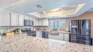 A modern kitchen with granite countertops, stainless steel appliances, and white cabinetry.