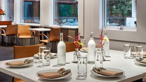 Een eettafel gedekt met borden, bestek, glazen en decoratieve vazen.