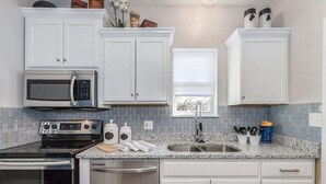 Una cocina con armarios blancos, microondas, estufa y lavavajillas.