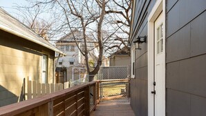 A narrow wooden deck leading to a garage door, surrounded by a chain-link fence and a white picket fence. - West Plaza House in the heart of KC (Kansas City)