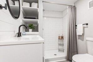Ein modernes Badezimmer mit Waschbecken, Spiegel, Dusche und Toilette.