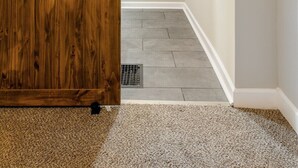 A hallway with a wooden sliding door, a tiled floor, and two framed pictures on the wall.