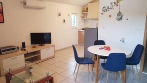 Un espacio habitable compacto con comedor, televisor y kitchenette.