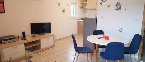 A compact living space with a dining area, a TV, and a kitchenette.
