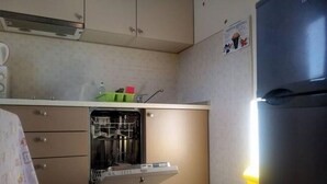 Una cocina compacta con lavavajillas, refrigerador y piso de baldosas.