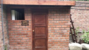 Ein Backsteinhaus mit einer Holztür und einem Schild, auf dem 'BAÑO' steht.