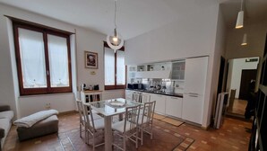 Eine moderne Küche mit weißen Schränken, einem Esstisch mit Stühlen und einer Pendelleuchte.