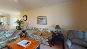 A living room with a sofa, a coffee table, a lamp, and a framed picture on the wall. - Magnolia Pointe Retreat with Pool & Golf Views | Magnolia Point Unit 201 (Myrtle Beach)