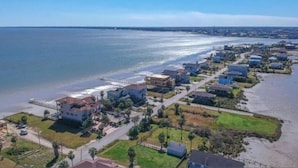 Luchtbeeld van een kustgebied met huizen, een strand en een steiger.