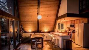 Una cucina accogliente con pavimento in legno, un tavolo da pranzo con sedie e un'ampia finestra con vista su un paesaggio innevato.