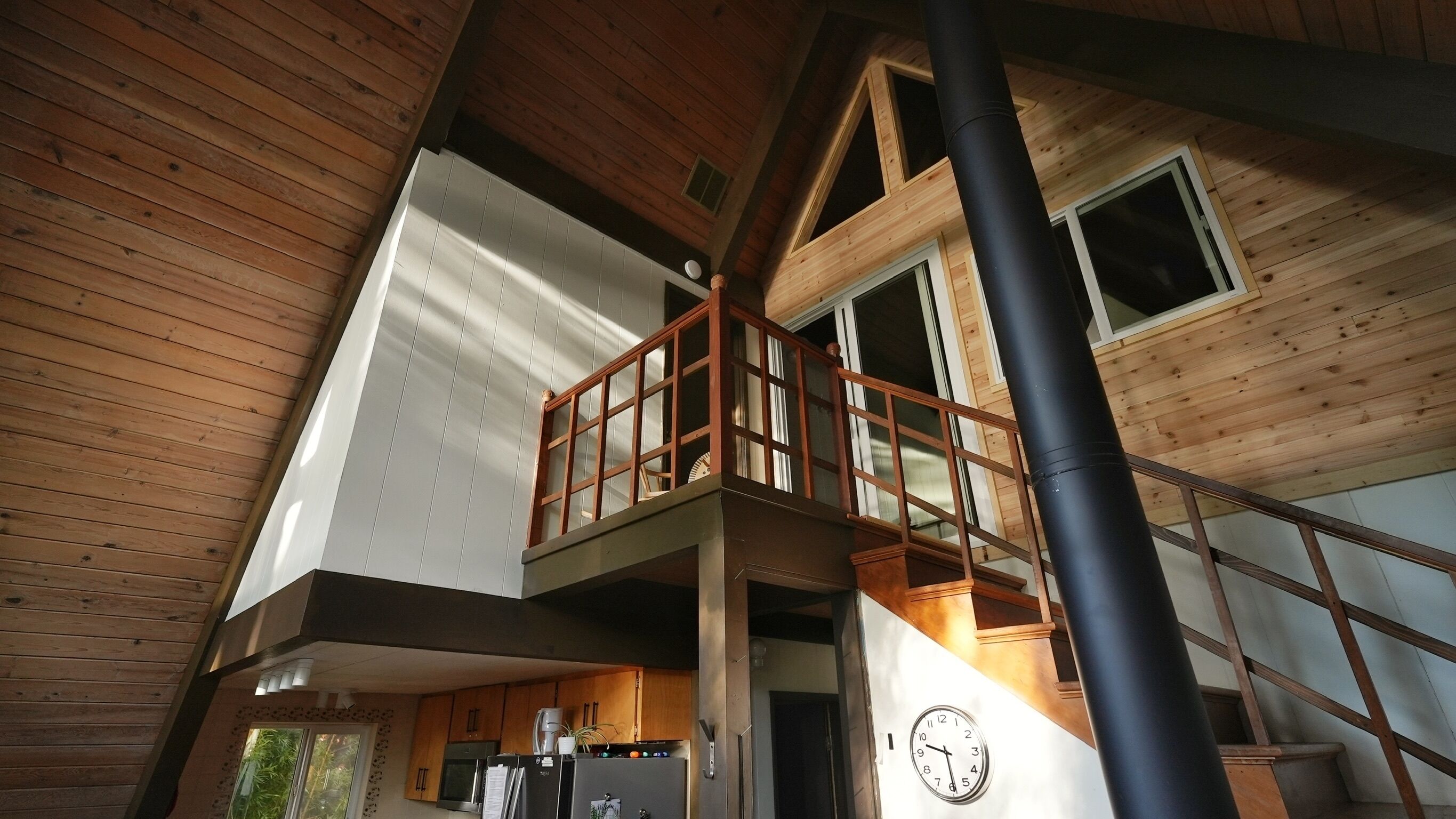 A multi-level wooden interior with a balcony, a clock, and a staircase.