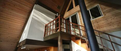 A multi-level wooden interior with a balcony, a clock, and a staircase.