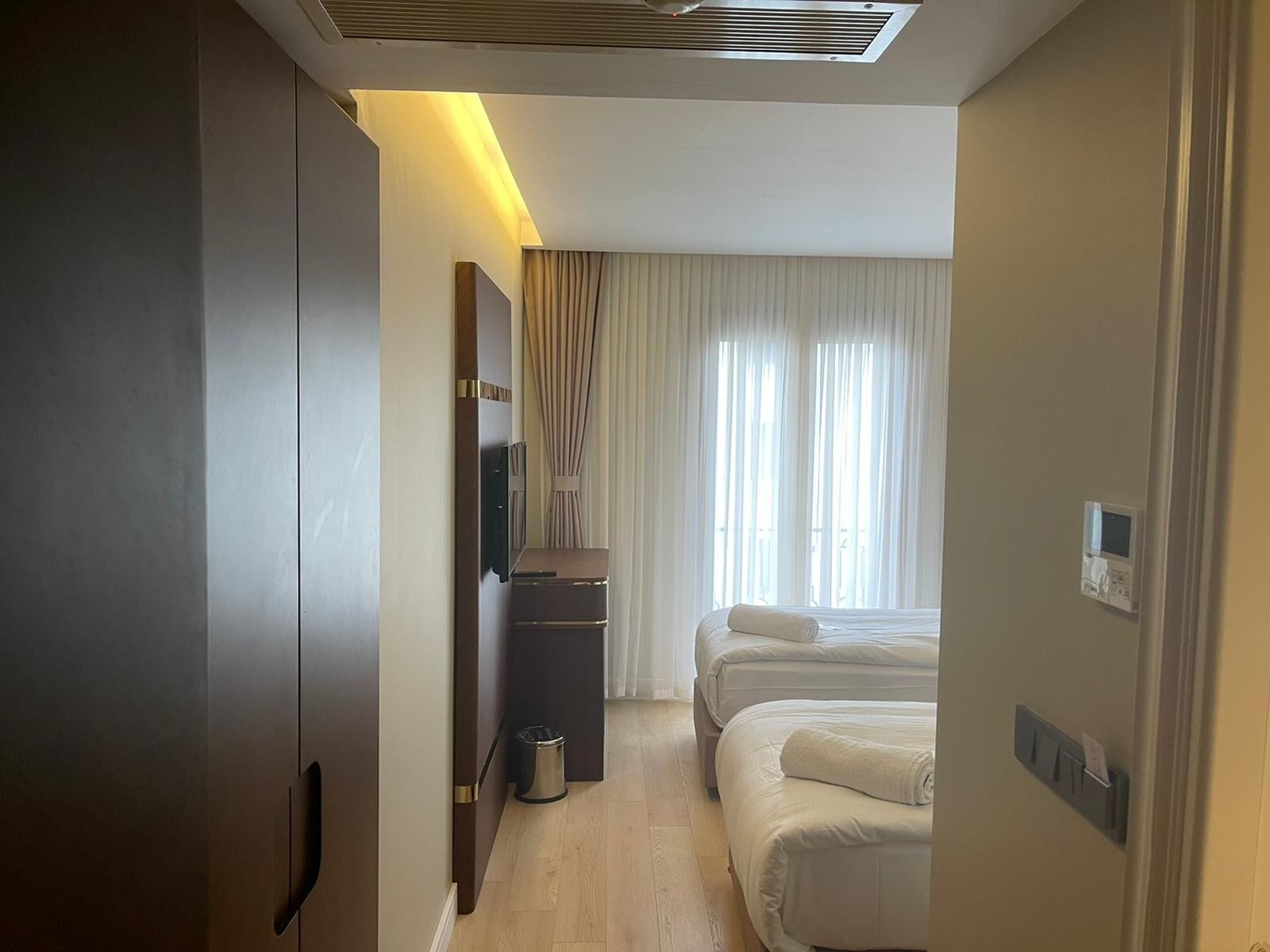 A hotel room with a bed, a desk, a TV, and a window with curtains.