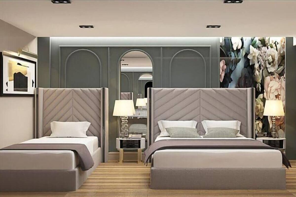 Een hotelkamer met twee bedden, een nachtkastje met lamp, een spiegel en een decoratieve wand met bloemen.