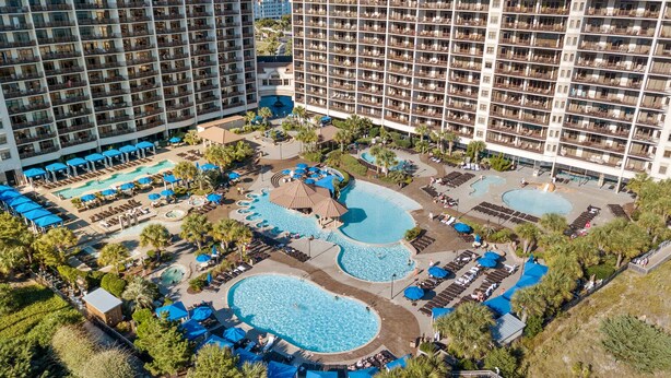 Un hotel con diverse piscine, lettini e ombrelloni.