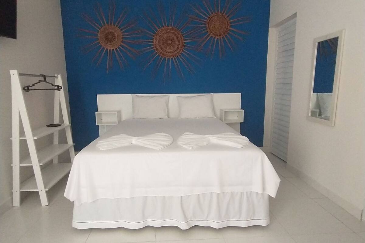 Ein Schlafzimmer mit einem Bett, einem weißen Kopfschild, einer blauen Akzentwand und einer weißen Leiter.