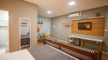 A modern bedroom with a large bed, a TV mounted on the wall, and a small desk area.