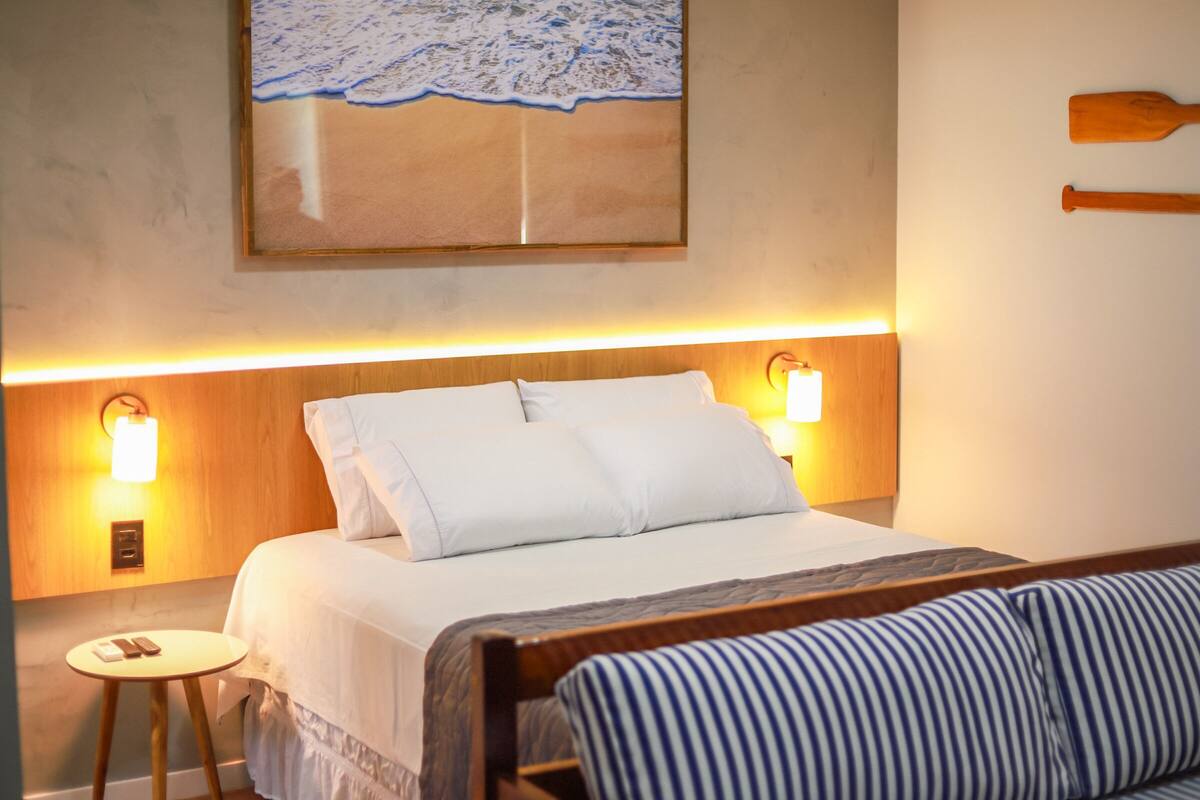 Ein Hotelzimmer mit einem Bett, Nachttischlampen, einem kleinen Tisch und einem Holzkopfteil.
