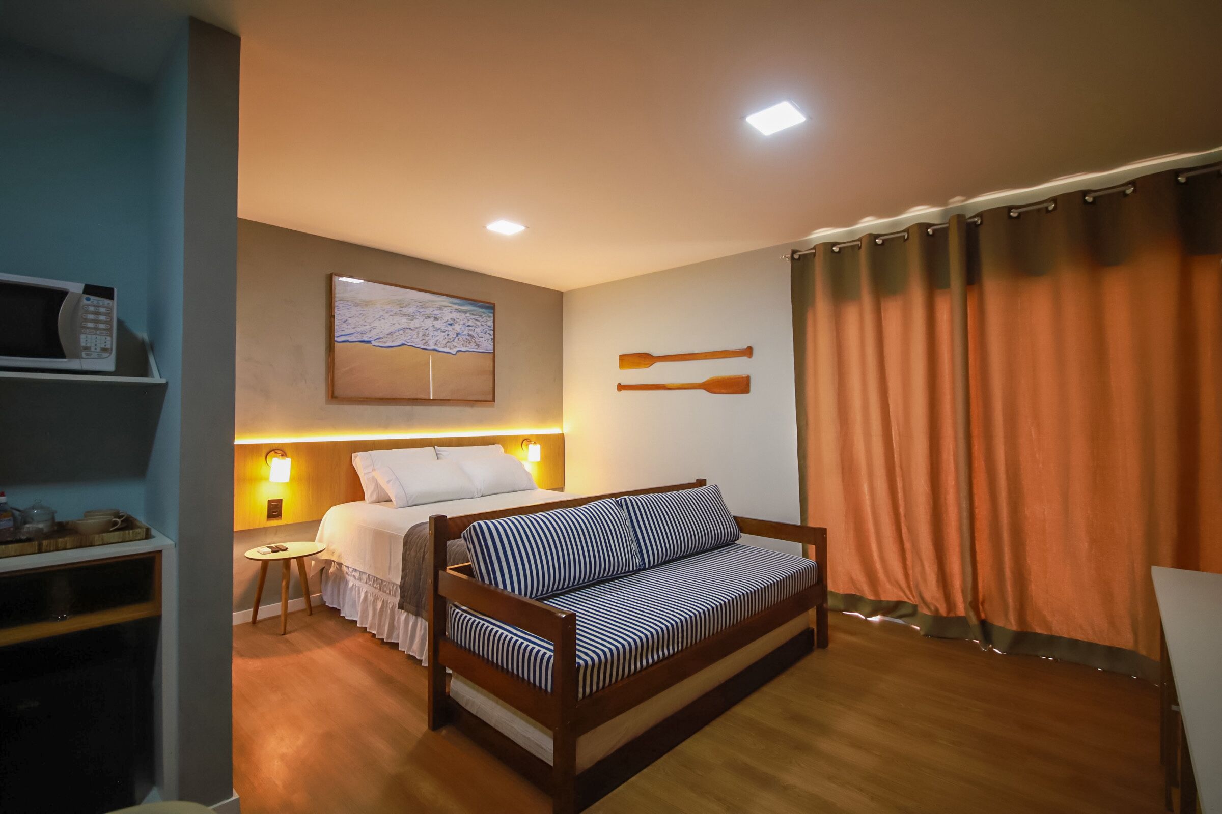 A hotel room with a bed, a sofa, a small table, and a microwave.