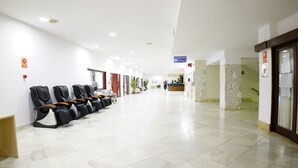 A clean, modern hallway with rows of massage chairs, a reception desk, and a staircase. - VIP Studio at Hotel Las Palmeras (Fuengirola)