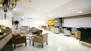 A spacious lobby with multiple seating areas, a reception desk, and a television screen. - VIP Studio at Hotel Las Palmeras (Fuengirola)