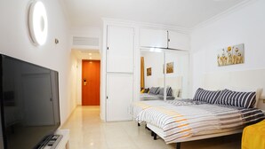 A bedroom with a bed, a TV, a wardrobe, and a painting on the wall. - VIP Studio at Hotel Las Palmeras (Fuengirola)