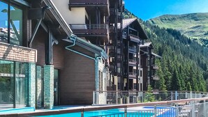 Ein Hotel mit Schwimmbad, Holzbalkonen und einer Bergkulisse.
