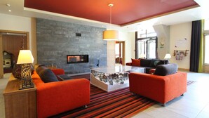 Eine moderne Lobby mit Steinwand, Flachbildfernseher, roten Sofas und einem Couchtisch.