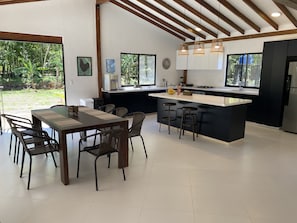 A modern kitchen with a central island, bar stools, and a dining table with chairs.
