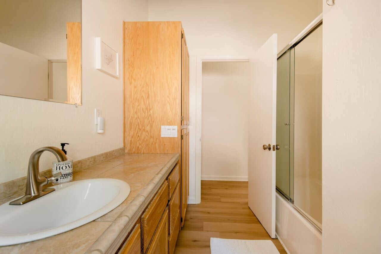 Une salle de bain avec un lavabo, un miroir, un meuble en bois et une porte de douche en verre.