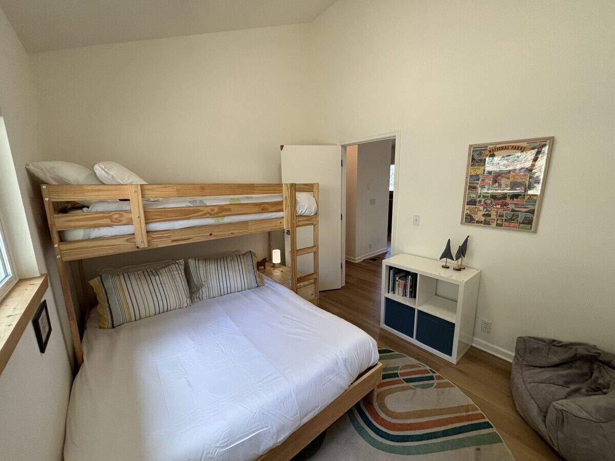 Ein gemütliches Schlafzimmer mit Etagenbett, kleinem Schreibtisch, Bücherregal und einem Poster an der Wand.