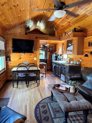 A cozy cabin interior with a dining area, kitchen, and seating space.