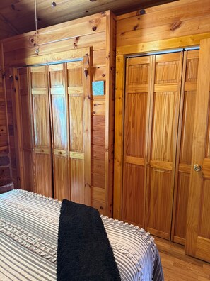 A wooden room with a bed, a wardrobe, and a map on the wall.