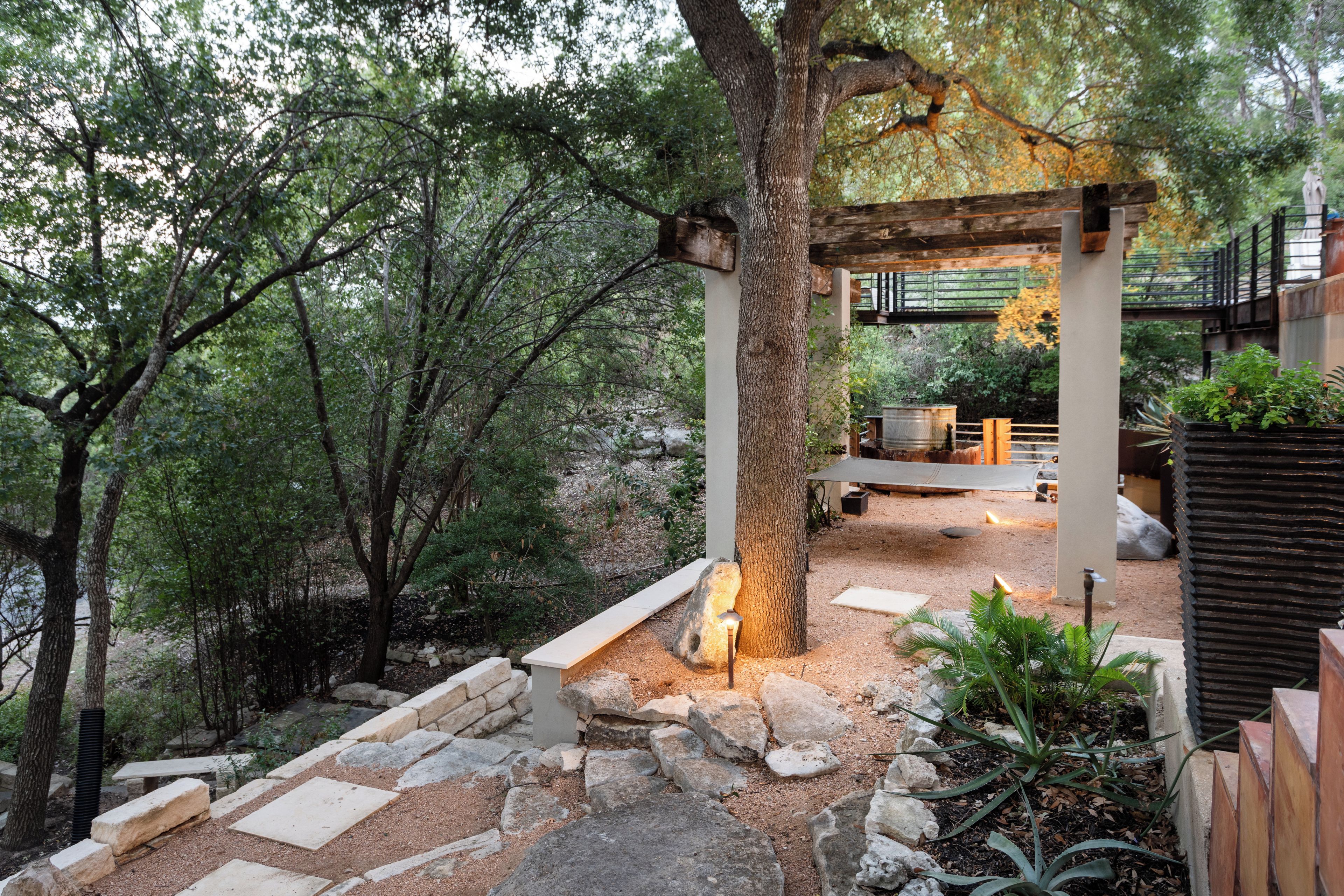 Un jardin agrémenté d’une pergola en bois, de sentiers en pierre et de diverses plantes.