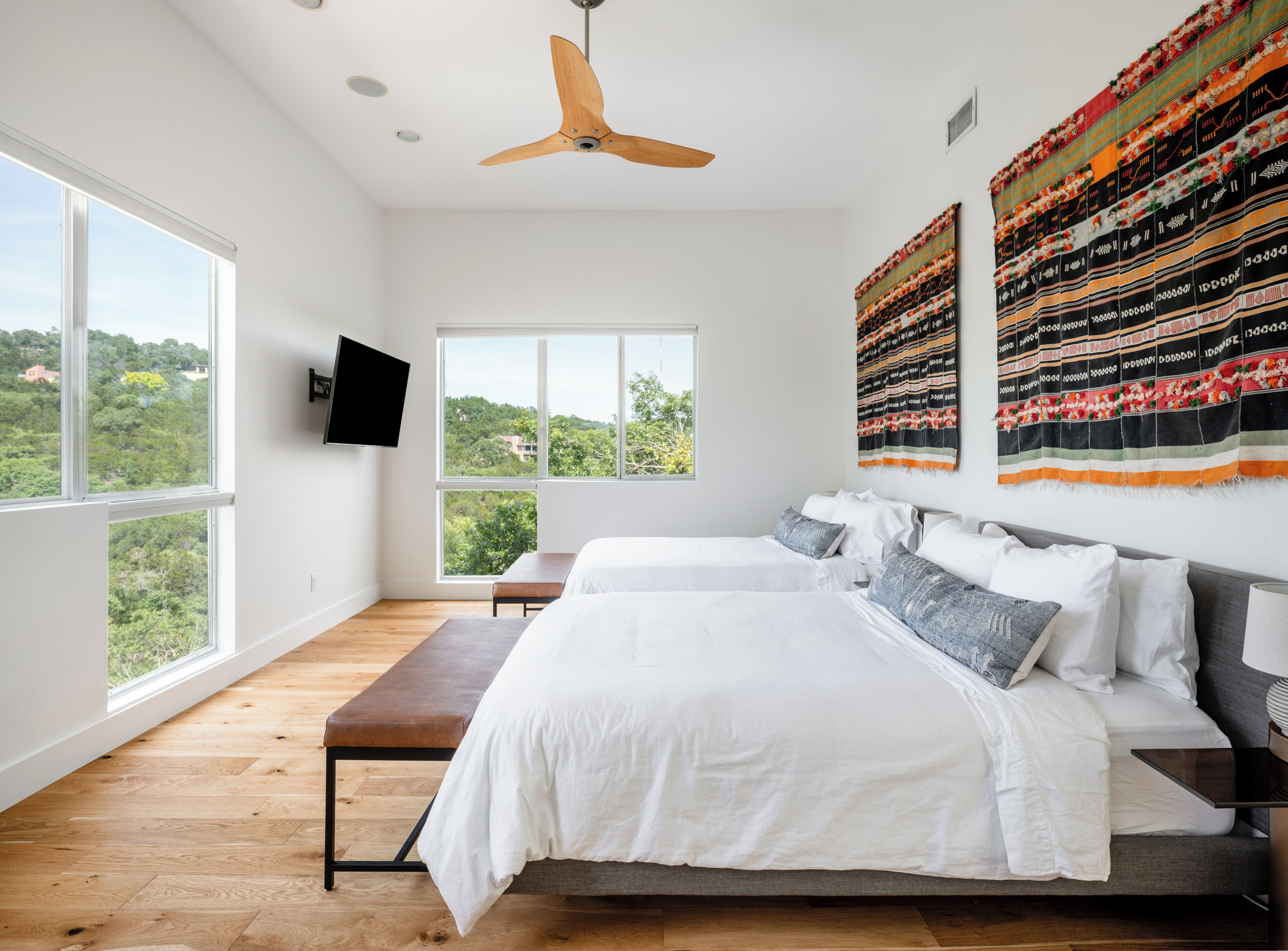 Une chambre moderne avec un grand lit, un banc et un ventilateur de plafond.