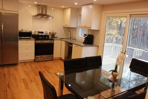 A modern kitchen with stainless steel appliances, a glass dining table, and a view of the outdoors.